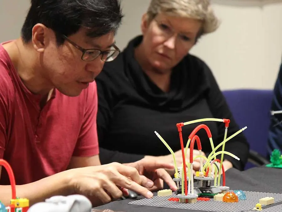 Participants building LEGO models at a workshop table